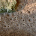 Sand floor beneath rock house lip has pitted impressions from repeated, steady water dripping.